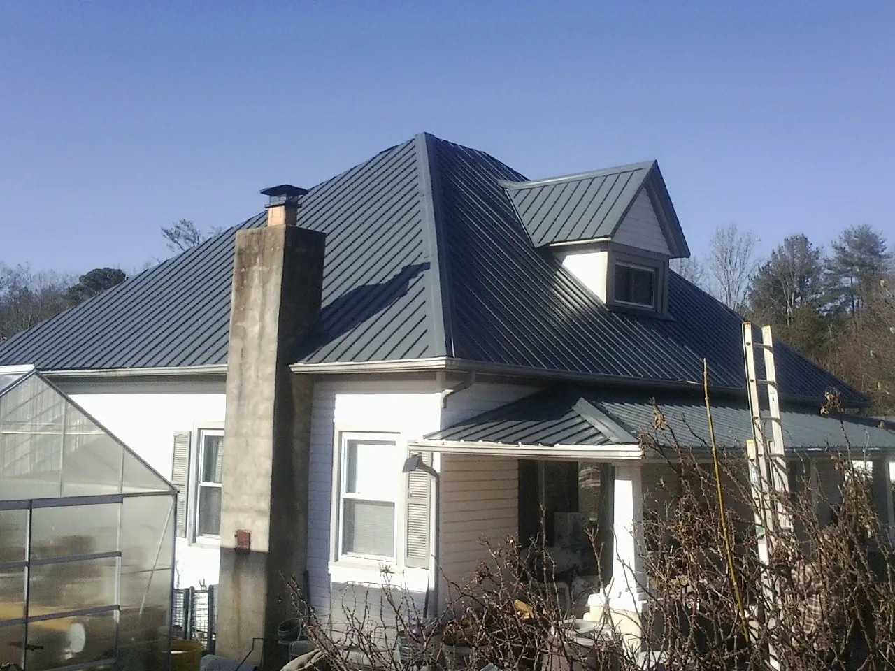 Dark blue standing seam metal roof on a white farmhouse with dormer — Slate & Tile Roof Repair by Roofing Brothers in Yacolt