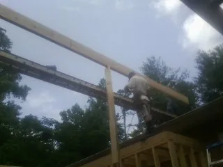 Carpenter setting a ridge beam over a new addition frame — Ice Dam Removal by Roofing Brothers in Yacolt
