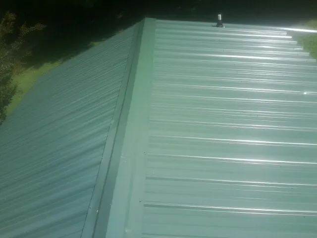 New green metal panels meeting at the ridge of a roof — Flat Roof Repair work by our crew in Yacolt