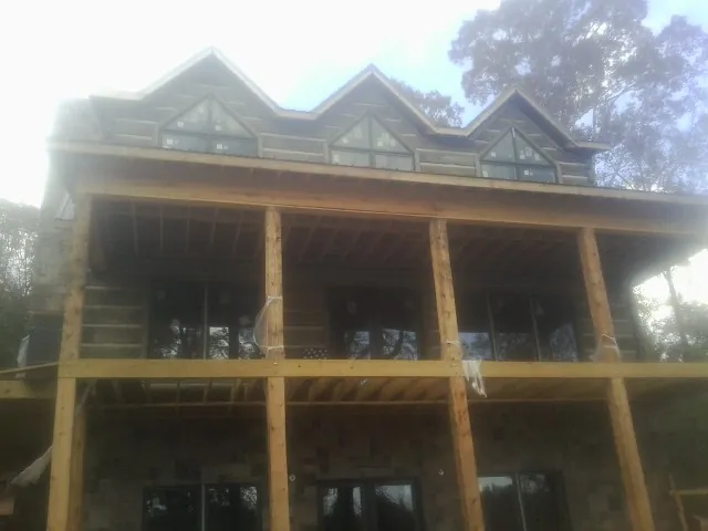 Dormers and porch framing on a large log home under construction — Roof Coating work by our crew in Yacolt