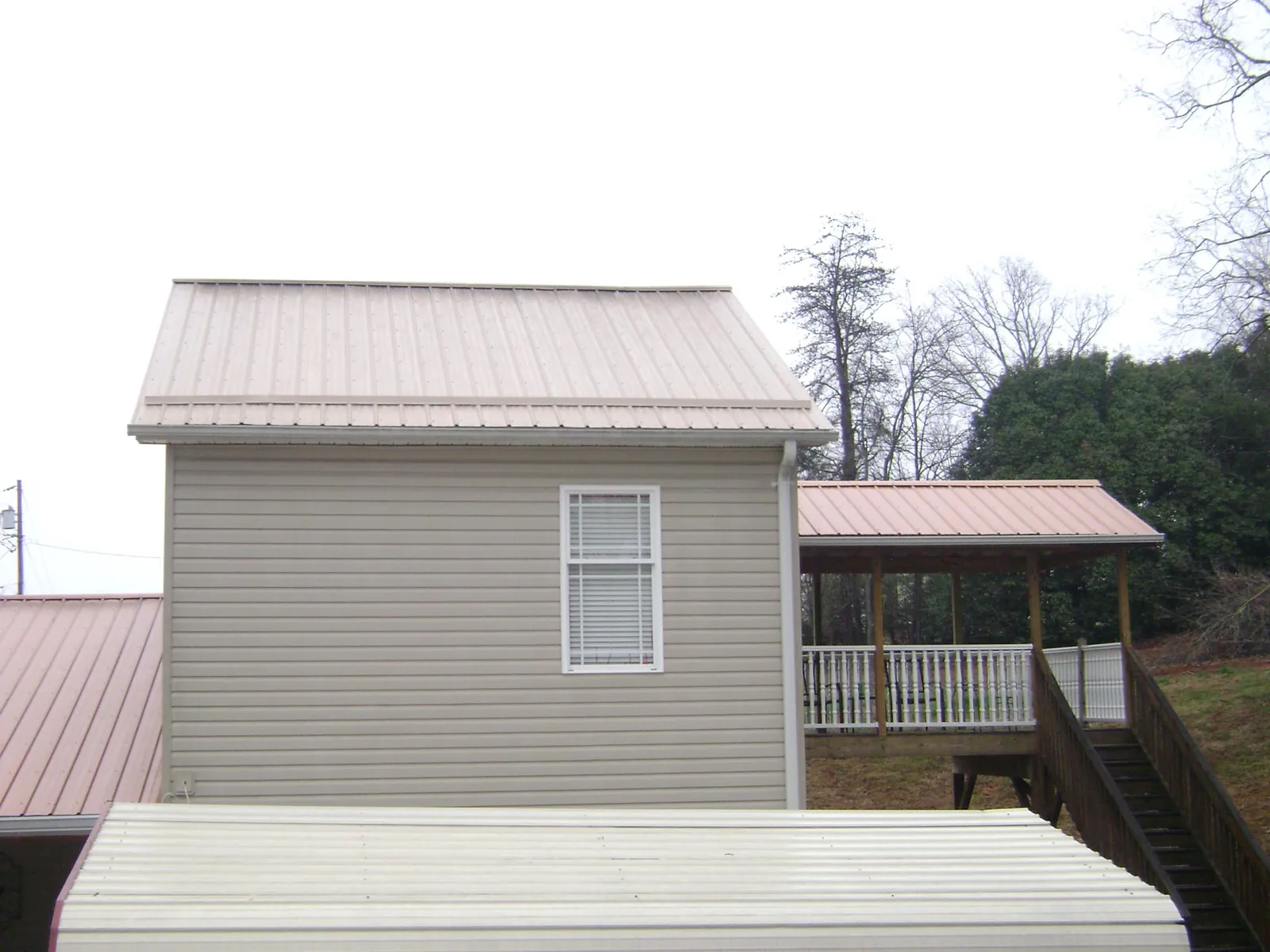 Tan metal roofs on a two story addition and attached porch, from a Roof Replacement job in Yacolt