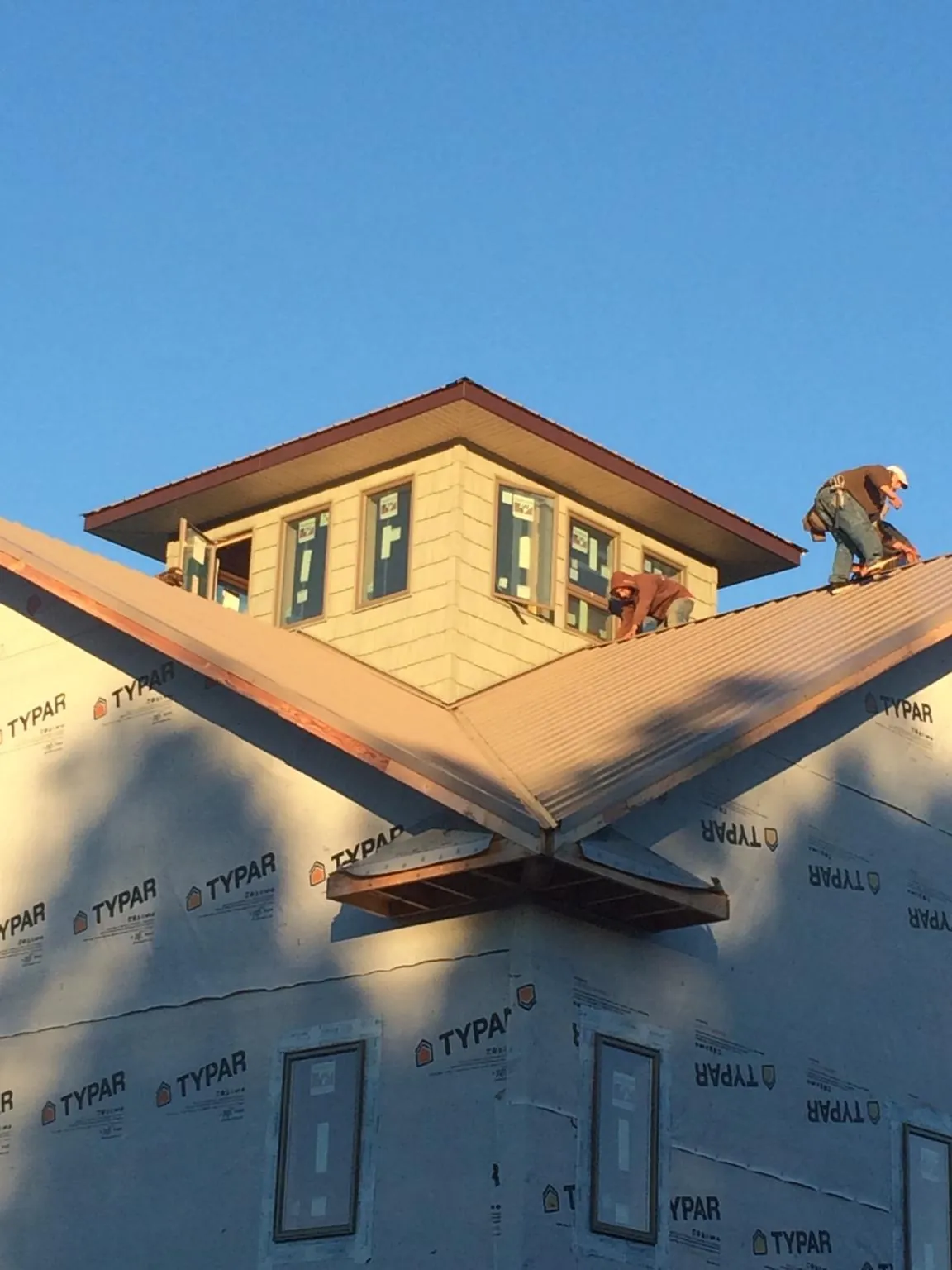 Roofers working around a rooftop cupola on a new metal roof at sunset — Roof Waterproofing in Yacolt by Roofing Brothers